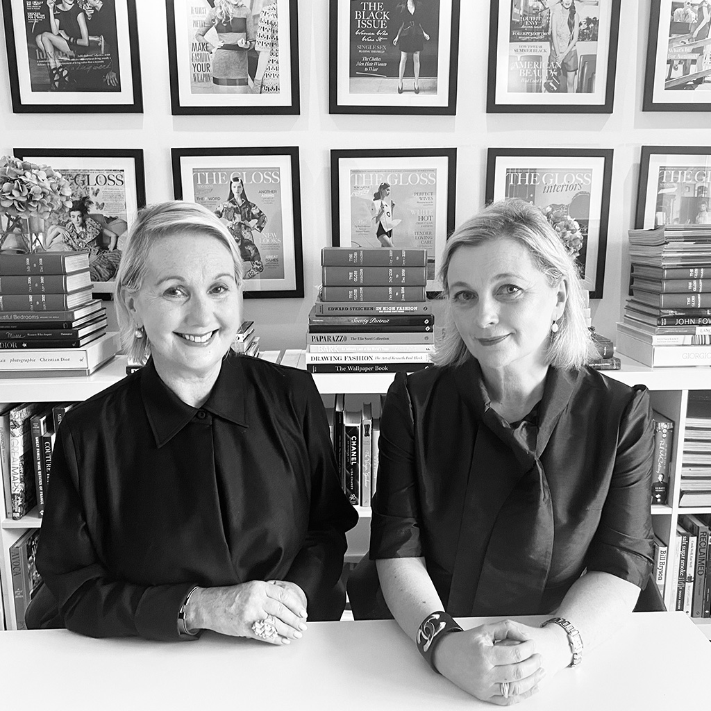 jane and sarah mcdonnell sitting at a desk with images of the gloss magazine covers framed behind them. both smiling to camera