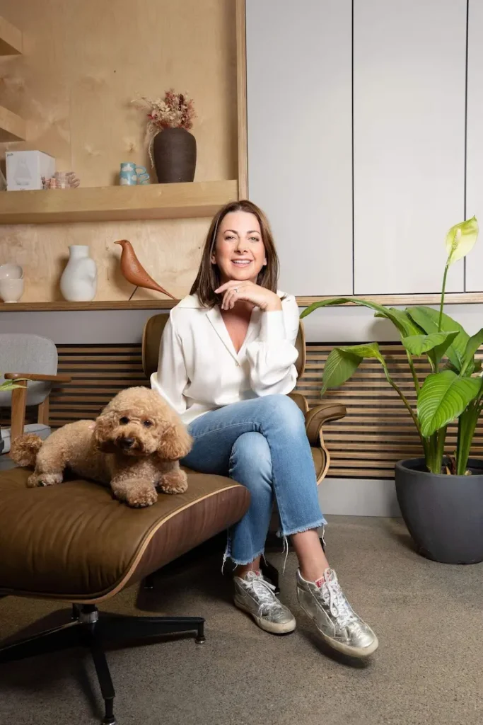 carol-anne leyden of ca design sitting with a dog in a design interior smiling to camera